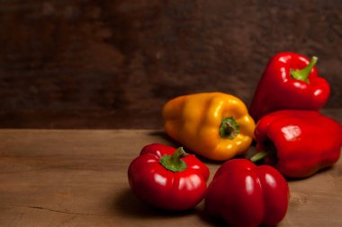 Sebze arkaplan resmi. Farklı şekillerde ve renkte olgun sulu dolmalık biberler eski ahşap arka planda.