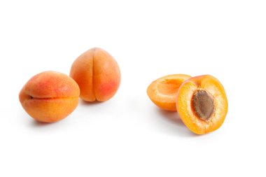 Beyaz arka planda iki tam ve yarım kayısı meyvesi.