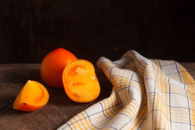 Eski ahşap arka planda kesilmiş, sulu sarı domates ve sarı havlu. Sebze koleksiyonu