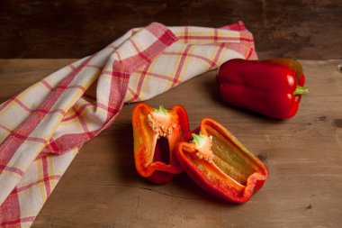 Tam ve yarım kırmızı dolma biber (capsicum) tatlı dolma biber olarak bilinir, kırmızı mutfak havlusuyla eski ahşap arka planda kırmızı biber.