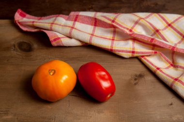 Kırmızı havluyla eski ahşap arka planda olgun kırmızı ve sarı domatesler. Sebze koleksiyonu