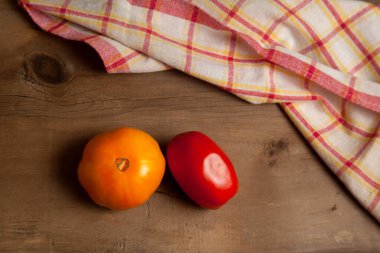 Kırmızı havluyla eski ahşap arka planda olgun kırmızı ve sarı domatesler. Sebze koleksiyonu