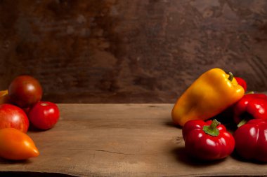 Sebze arkaplan resmi. Farklı şekil ve renkte olgun sulu domatesler ve eski ahşap arka planda dolmalık biber.