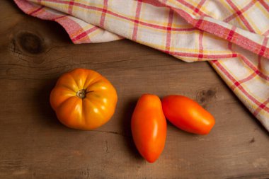 Ahşap zemin üzerinde kırmızı havlu olan olgun, sulu sarı domatesler. Sebze koleksiyonu