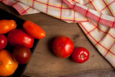 Kırmızı havluyla olgun, sulu, kırmızı ve sarı domateslerle dolu bir kase. Sebze koleksiyonu