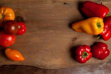Sebze arkaplan resmi. Farklı şekil ve renkte olgun sulu domatesler ve eski ahşap arka planda dolmalık biber.