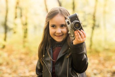 Sonbahar doğasında eski moda kamera kullanan bir kız çocuğu. Fotoğrafçı, sonbahar sezonu ve eğlence konsepti