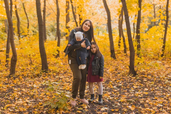 在公园里散步的时候 戴眼镜的白人妈妈正在和她的儿子和女儿玩树叶游戏 — 图库照片