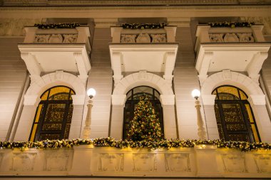 Işıklarla süslenmiş Noel ağacı ve şehir merkezindeki bir balkonda mücevherlerle süslenmiş toplar ve yeni yıl çelenkleri. Xmas dekorasyonları