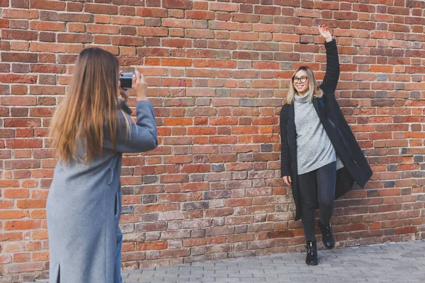소녀는 거리의 앞에서 자신의 친구의 사진을 찍는다 사진사 이자젊은 — 스톡 사진