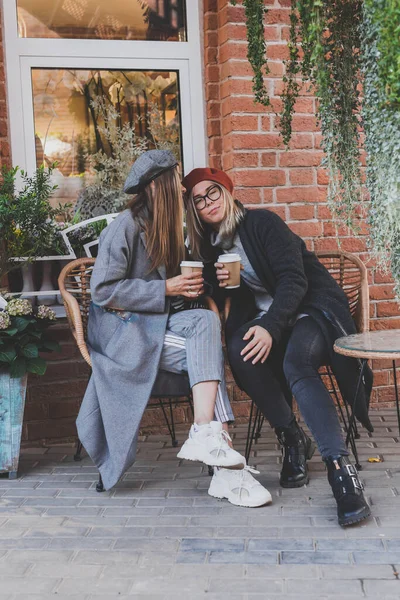 自由な時間のヒップスターの女の子の間に興味深いテーマを議論し 冗談を言い 一緒に都市に行くためにコーヒーとレクリエーションを楽しんで楽しんでいる若い女性の親友 — ストック写真