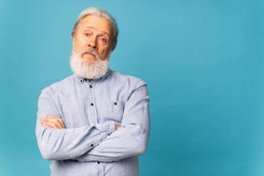 Şaşırmış gri saçlı sakallı büyükbabanın portresi mavi arkaplanlı yaşlı adam