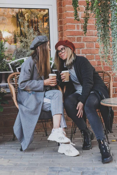 自由な時間のヒップスターの女の子の間に興味深いテーマを議論し 冗談を言い 一緒に都市に行くためにコーヒーとレクリエーションを楽しんで楽しんでいる若い女性の親友 — ストック写真