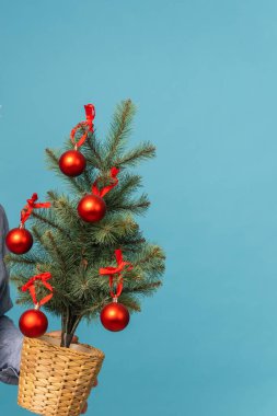 Mavi arka planda kırmızı toplar ve takılar süslenmiş küçük Noel ağacı - xmas ve kış tatili