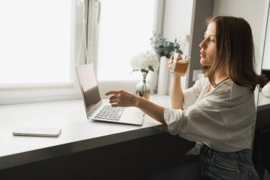 Genç ve güzel bir bayanın internette yazdıktan sonra çay içip bilgisayarda dolaşırken rahat bir odada tek başına oturması. Mesafe öğrenme ve mola ile çalışma