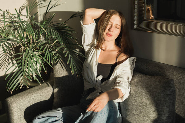 Портрет молодой красивой женщины у окна с тенью от цветов на лице. Эстетика утренней весны