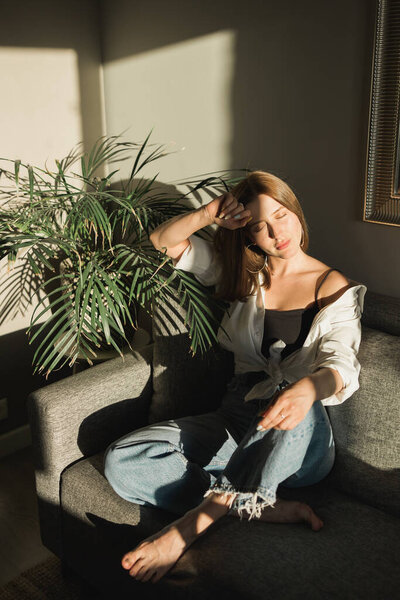 Портрет молодой красивой женщины у окна с тенью от цветов на лице. Эстетика утренней весны