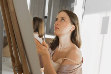 Genç kadın ressam yatak odasındaki sehpada resim yapıyor. Sanat ve yaratıcılık.