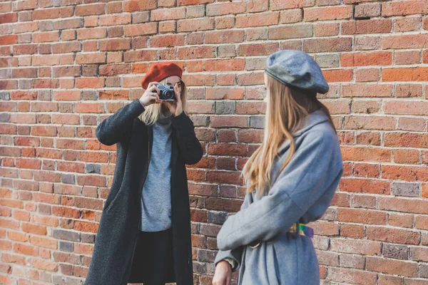 Девушка Фотографирует Свою Подругу Перед Кирпичной Стеной — стоковое фото