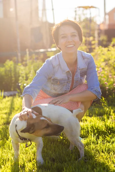 stock image Young woman plays with her dog on the grass on backyard. The concept of animals and friendship or pet owner and love.