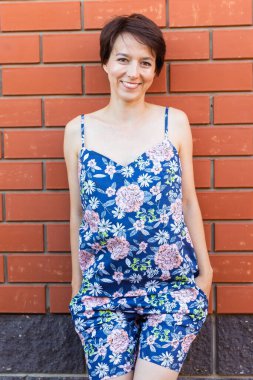 Evdeki neşeli kadın pijamasını giyer tuğla duvar arkası duyguları - pijama ve ev kıyafetleri