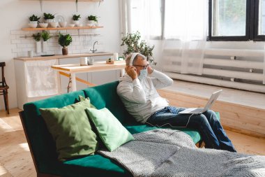 Yaşlı, gümüş saçlı yaşlı adam Coronavirus yüzünden yüz maskesi takıyor. Modern teknoloji ve emekli.