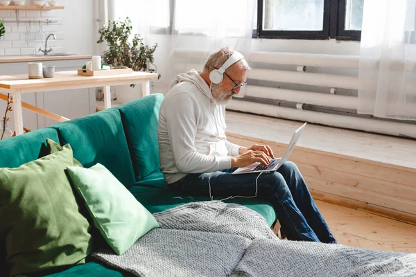 Jóképű Öregember Kapucnis Pulcsiban Szemüvegben Laptopot Használ Mosolyog Miközben Zenét — Stock Fotó