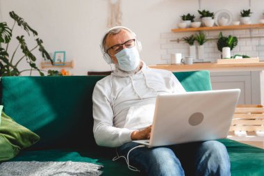Yaşlı, gümüş saçlı yaşlı adam Coronavirus yüzünden yüz maskesi takıyor. Modern teknoloji ve emekli.