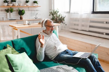 Yaşlı bir adam laptopta çocuklarla görüntülü konuşma yapıyor. Modern teknoloji iletişim interneti.