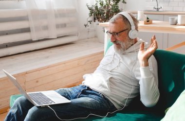Yaşlı bir adam laptopta çocuklarla görüntülü konuşma yapıyor. Modern teknoloji iletişim interneti.