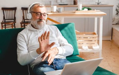 Yaşlı bir adam laptopta çocuklarla görüntülü konuşma yapıyor. Modern teknoloji iletişim interneti.