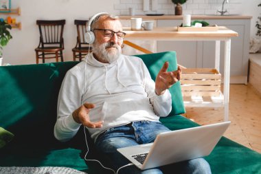 Yaşlı bir adam laptopta çocuklarla görüntülü konuşma yapıyor. Modern teknoloji iletişim interneti.