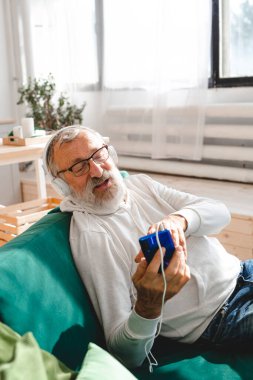 Yaşlı adam, havalı sakallı yaşlı adam video görüşmesi için cep telefonu kullanıyor. Mutluluk, yaşlılar yaşam tarzı kavramı. Akıllı telefondan çocuklara el sallayıp sohbet eden bir video. Modern.