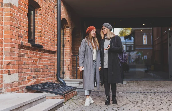 二人の女の子が一緒に通りを歩いて手を握っています 春や秋の服を着て 喜んでいます 友情と関係の概念 — ストック写真