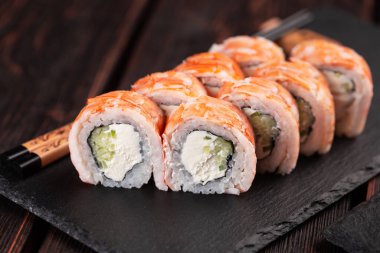 Japanese kitchen - sushi roll with cucumber and cream cheese topped with shrimp black board
