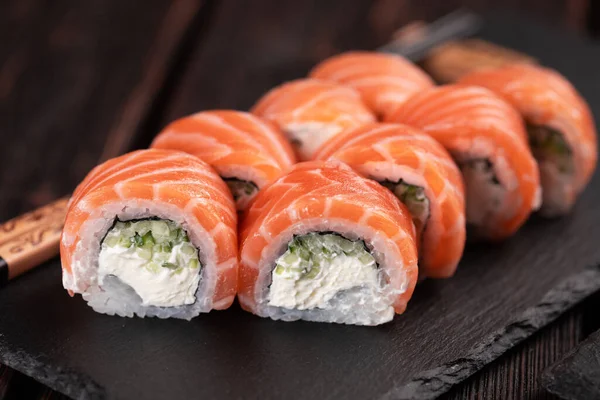 Sushi roll philadelphia with salmon and cucumber and cream cheese on black background. Sushi menu. Japanese food