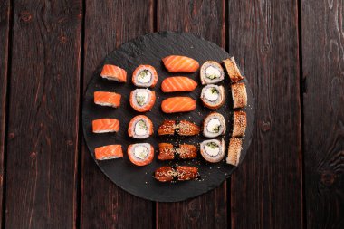 Large sushi set from top on black background. Assortment of various maki nigiri and rolls seafood soy sauce