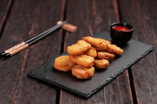 Fried chicken pieces on stone board with chopsticks - asian food.