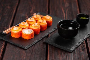 California sushi roll with crab, avocado, cucumber and tobiko caviar served on black board - Japanese food.