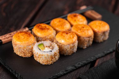 California sushi roll with crab, avocado, cucumber and tobiko caviar served on black board - Japanese food.