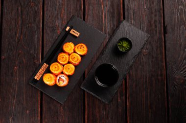 California sushi roll with crab, avocado, cucumber and tobiko caviar served on black board - Japanese food.