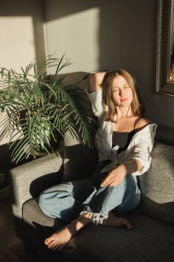 Pencerenin yanında, yüzünde çiçeklerin gölgesi olan güzel bir kadının portresi. Sabah ilkbahar estetiği