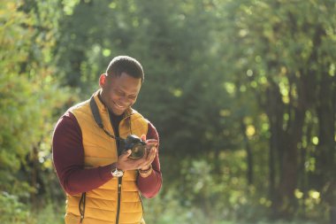 Afro-Amerikalı fotoğrafçı, yeşil parktaki klasik kamerayla fotoğraf çekiyor. Boş zaman aktivitesi, çeşitlilik ve hobi.