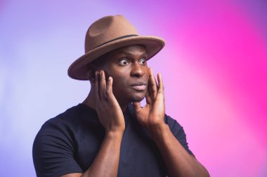 Portrait of excited young African American male screaming in shock and amazement holding hands on head. Surprised bug-eyed black hipster looking impressed, cant believe his own luck and success