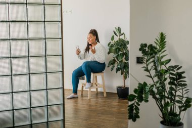 African american woman making video call, in kitchen - social networks
