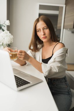 Genç ve güzel bir bayanın internette yazdıktan sonra çay içip bilgisayarda dolaşırken rahat bir odada tek başına oturması. Mesafe öğrenme ve mola ile çalışma