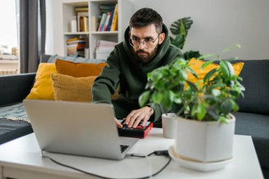 Top view of music producer or arranger using laptop, midi keyboard, and other audio equipmen to create music at home studio. Beat making, arranging audio content, composing song