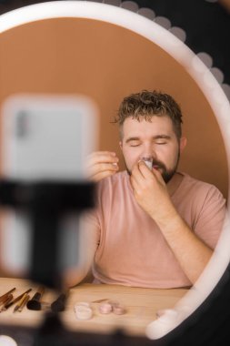 Ünlü blogcu. Video kaydederken kozmetik ürünlerini gösteren ve güzellik blogu için tavsiyelerde bulunan neşeli bir erkek vlogcu. Makyaj sanatçısı ve Güzellik vlog 'u