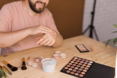 Erkek güzellik blogcusu makyaj yapıyor ve cep telefonuyla bir video dersi kaydediyor - vlog, çeşitlilik ve video blogu