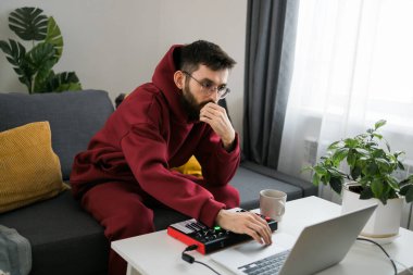 Top view of music producer or arranger using laptop, midi keyboard, and other audio equipmen to create music at home studio. Beat making, arranging audio content, composing song